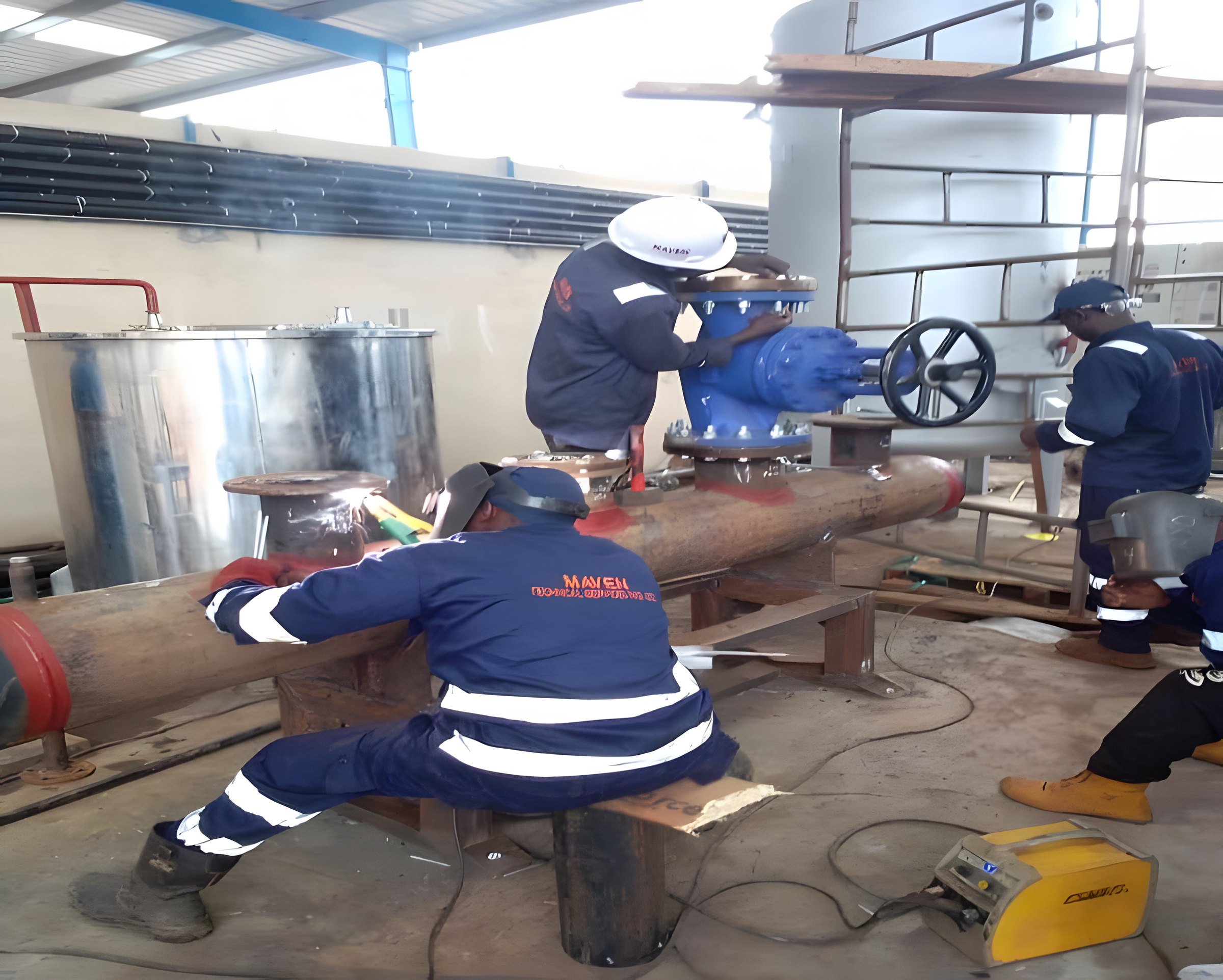 Welder joining a pipe header in the open before weld inspection and testing