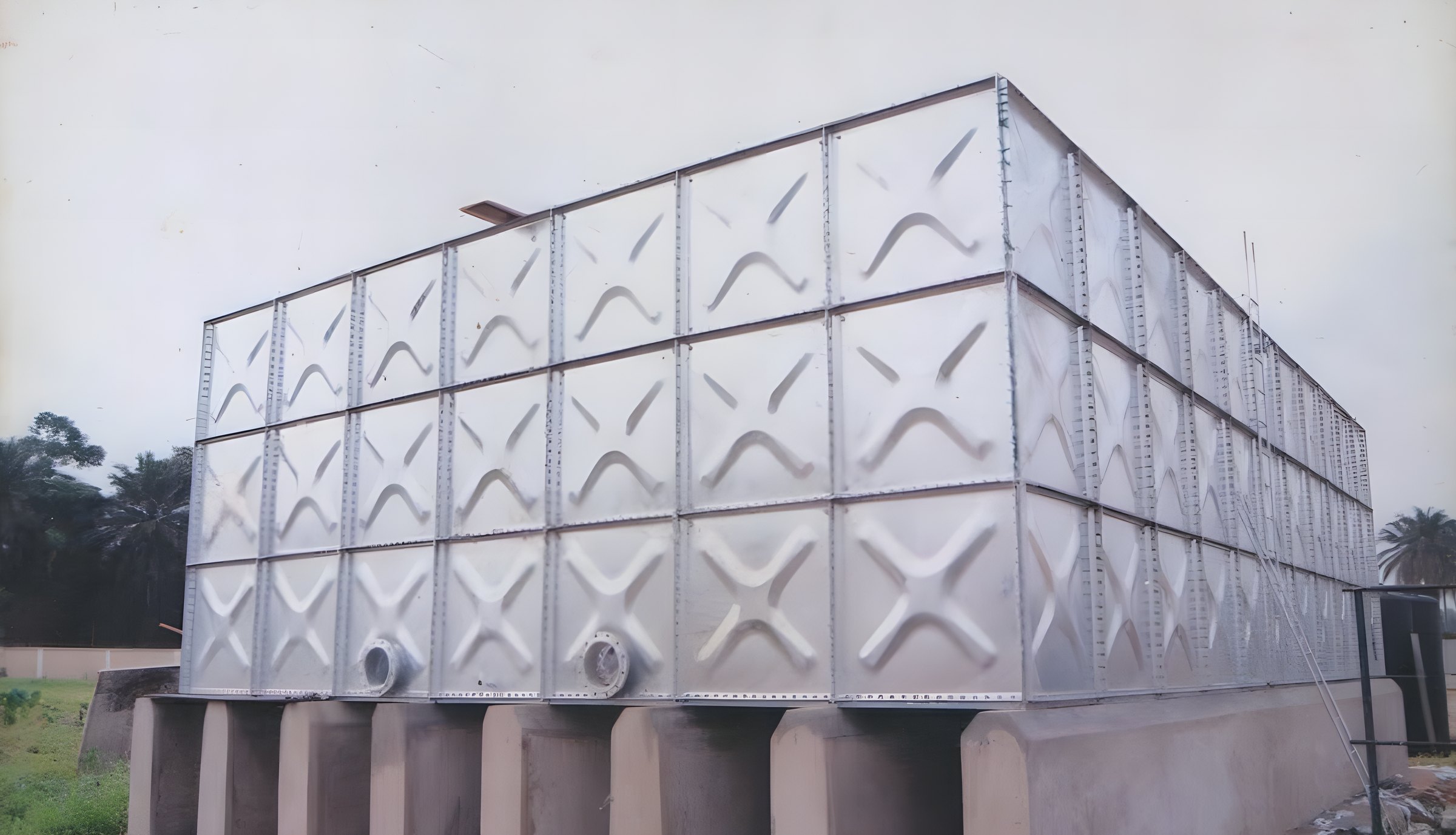 Galvanised pressed steel tank standing on concrete piers at an industrial site